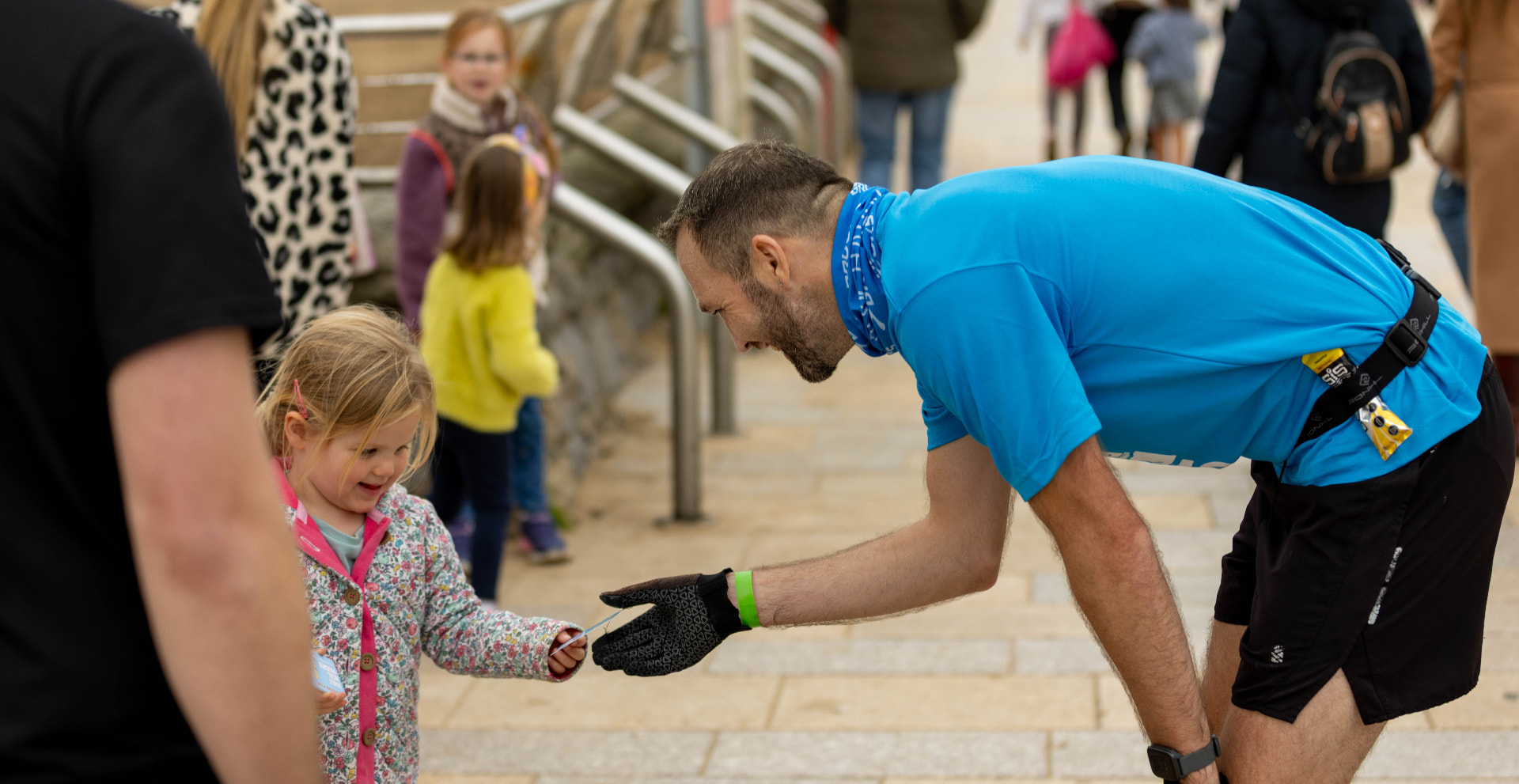 A finisher handing a medal to a young supporter at the Grand Pier