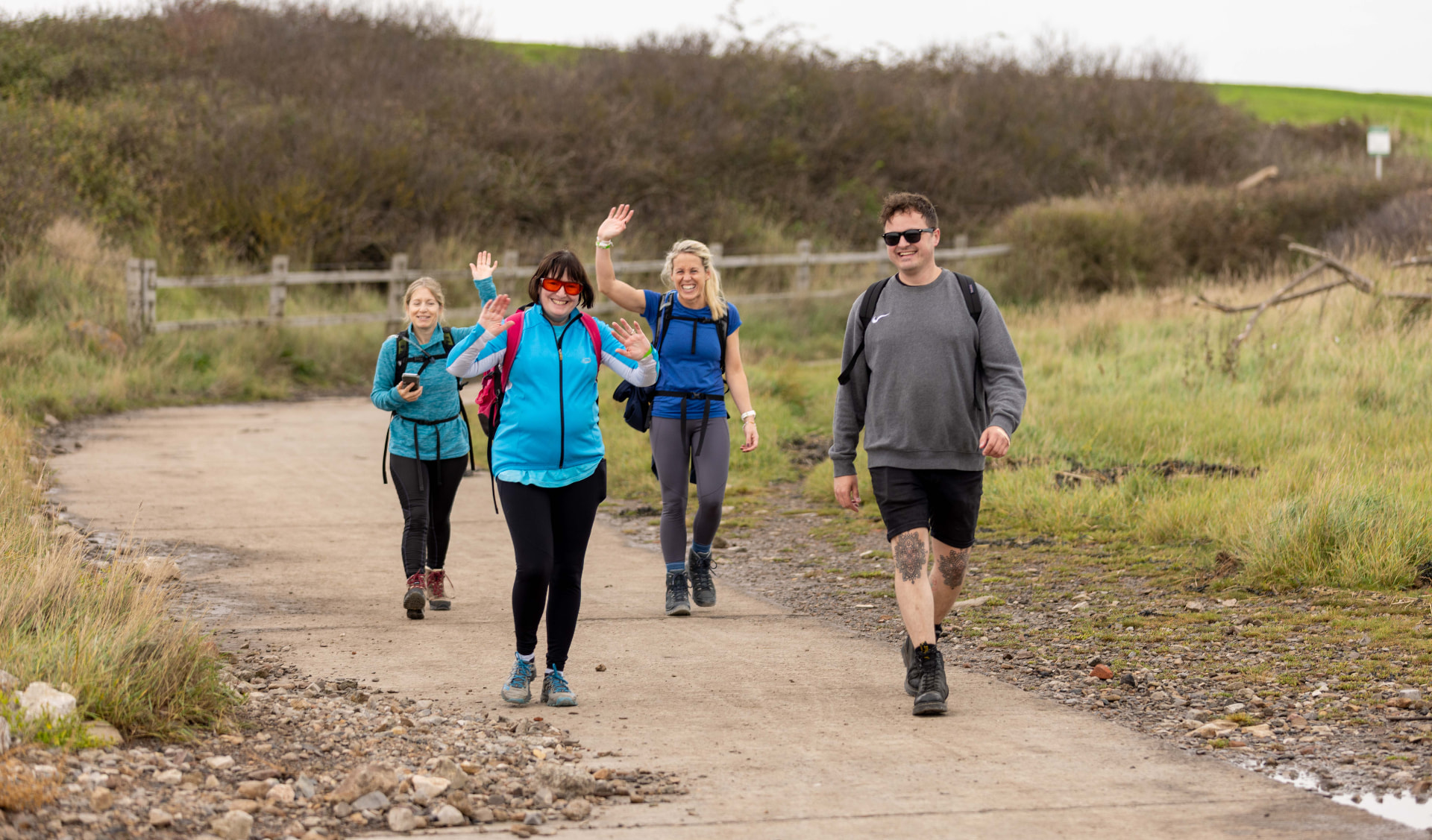 A group of walkers waving on the coastal path